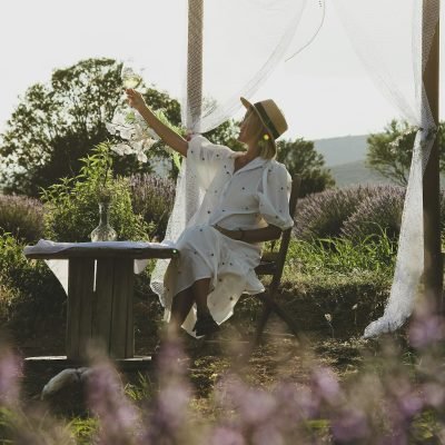 girl drinking wine sitting at a table in a lavender field